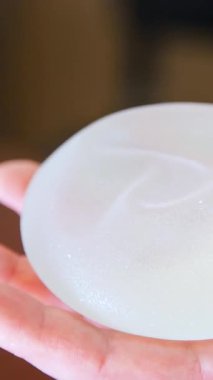 Göğüs implantı. Silikon dişi göğüs implantı. Doktor silikon göğüs implantı gösteriyor. Dikey video.