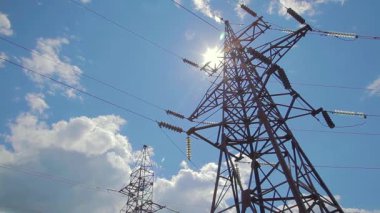 Elektrik iletimi kablolarla yapılıyor. Mavi gökyüzü ve uçan bulutların arka planında kablolar ve yalıtıcılarla yüksek voltaj destekliyor. 