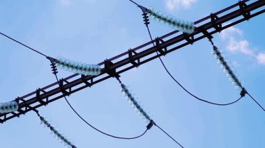 Video seti: Mavi gökyüzü ve uçan bulutların arka planına karşı kablolar ve izolatörlerle yüksek voltaj destekler. Elektrik kabloları ile iletimi.