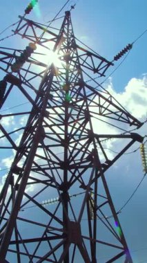 Kablolar ve izolatörlerle yüksek voltajlı destekleri mavi gökyüzü ve uçan bulutların arka planına karşı. Elektrik iletimi kablolarla yapılıyor. Dikey video.