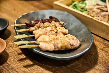 Yakitori ahşap bir masada bir tabakta servis yapıyordu. Mükemmel ızgara tavuk ve domuz şişleri tüm ihtişamıyla sunuluyor, rahat ve dost canlısı bir atmosferle çevrili..