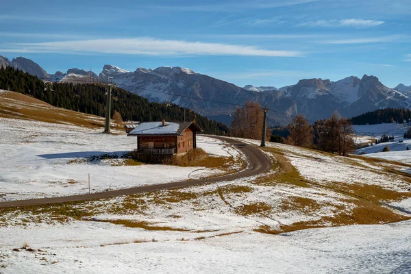 İtalya 'daki Dolomitler' de uzun, karlı bir dağın arkasında teleferik direkleri olan bir kulübe..