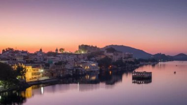 Gündoğumunda Udaipur şehir manzarası. Görkemli şehir sarayı ve Pichola Gölü 'nde giden tekneler, Hindistan, Rajasthan' a seyahat ediyor. Zaman aşımı.