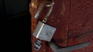 Demir kale. Kilit kapıda asılı duruyor. Kilit ve anahtar. Anahtar kilidin içinde. Tahta bir kapının kilidi.