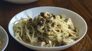 Tabakta spagetti. Mantarlı bir tabakta spagetti pişirdim. Tahta bir masada beyaz tabak.