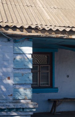 Köydeki eski ev. Banka pencerenin yanında duruyor. Köyde bir evin dışında.