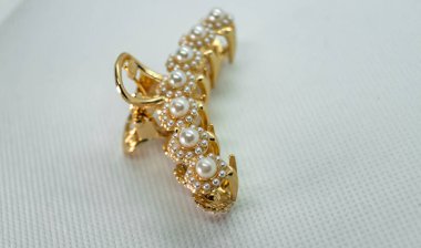 İncili büyük altın bir saç tokası. Beyaz arka planda incili altın metal saç pençesi