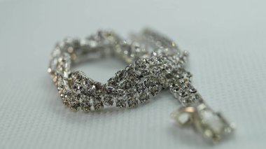 Beyaz arka planda küçük parlak taşlar olan bir bilezik.