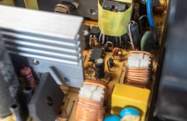Güç kaynağı indüktörü bakır bir kabloyla sarılmış. Mikroçip rezistörleri ve tozlu elektronik bileşenler