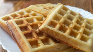 Tahta bir masada beyaz bir tabakta Belçika waffle 'ı. Belçika waffleları yakın plan