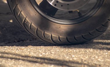 Güneş ışığında asfalt üzerinde paspaslı tekerlek. Asfalttaki harita çarkının yan görünümü