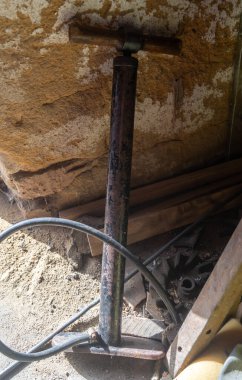 Paslı bir pompa eski bir kil duvara yaslanıyor.