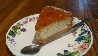 Tabağın üstünde küçük bir kaşıkla soslu cheesecake.