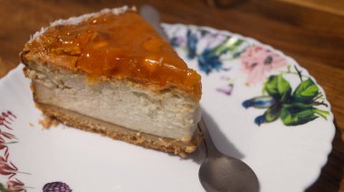 Tabağın üstünde küçük bir kaşıkla soslu cheesecake.