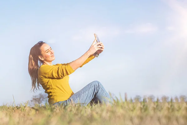 stock image Woman is smiling in yellow take selfie on phone outdoor