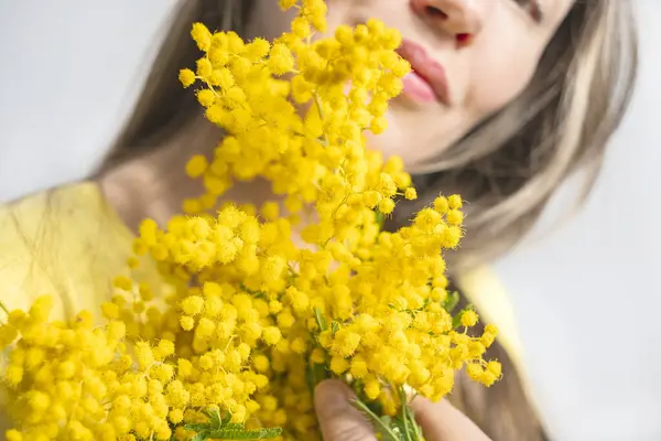 Beautiful young woman with mimosa flowers on white background. Close up