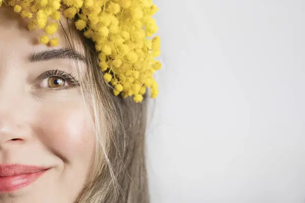 Portrait of Beautiful young woman with mimosa flowers on white background. Close up