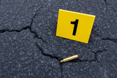 Sokağın ortasında sarı bir suç mahalli delili var. Silah atışı sonrası mermi kovanı tüfeği.