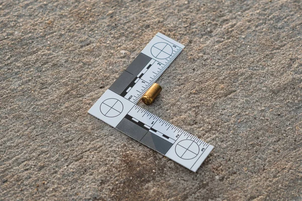 Bir olay yeri kanıt cetveli, 9 mm 'lik kovan ve 9 mm' lik tabanca mermisinden sonra sokaklardaydı.