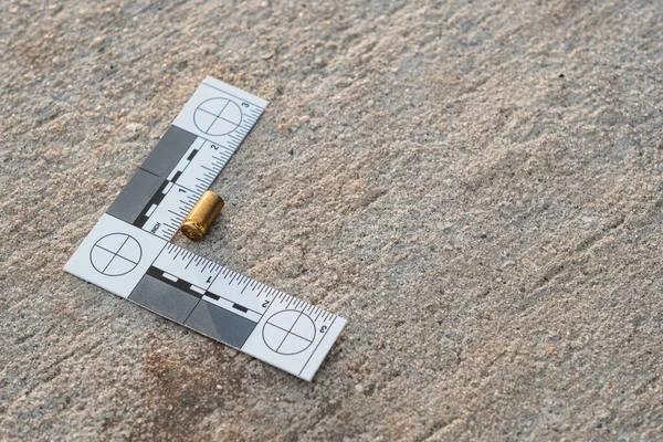 Bir olay yeri kanıt cetveli, 9 mm 'lik kovan ve 9 mm' lik tabanca mermisinden sonra sokaklardaydı.