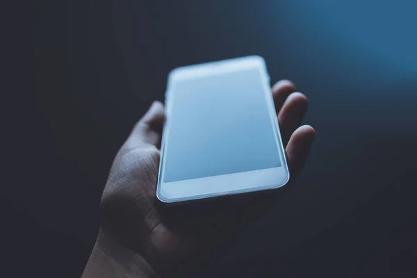 Beyaz bir cep telefonunu tutan bir insan eli.