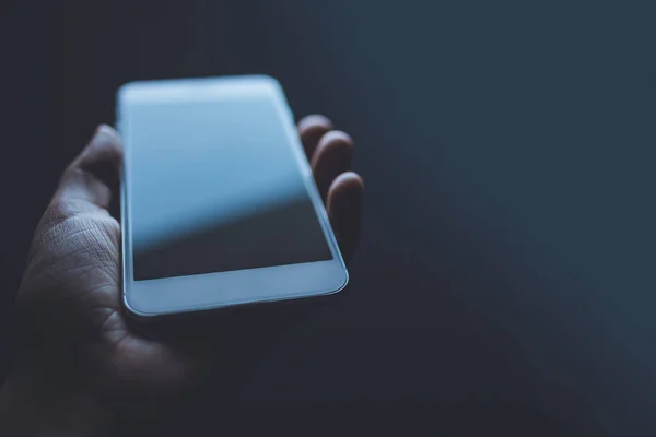 Beyaz bir cep telefonunu tutan bir insan eli.