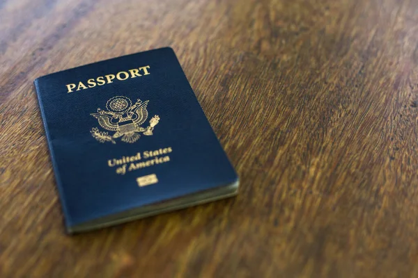 Ahşap bir masanın üzerinde duran mavi bir Amerikan pasaportu.