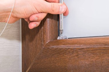 Kahverengi plastik pencereye panjur takan bir adamın görüntüsü