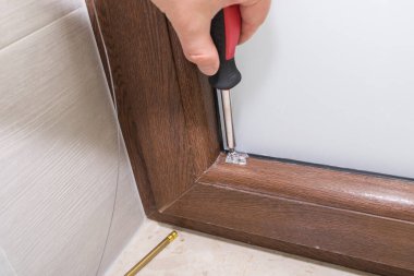 Kahverengi plastik pencereye panjur takan bir adamın görüntüsü