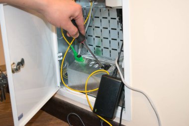 Yönlendirici kutusu açık, insan eli tornavida tutuyor, yanında da siyah bir yönlendirici var.