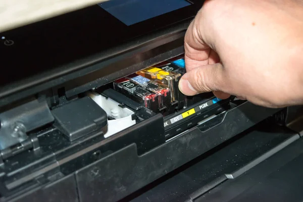 Replacing the ink in the printer, the human hand takes out the cartridge