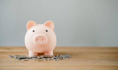 Pembe domuz kumbarası, bej arka planda ahşap masada madeni paralar. Tasarruf, depolama, birikim, kriz, enflasyon, finansal çöküş, kopyalama alanı olan işletme ve finans kavramı.