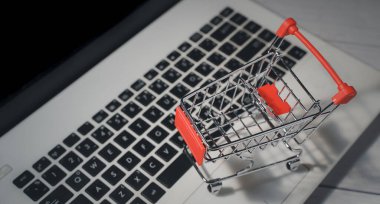 Shopping online. Trolley in front laptop keyboard. Business retail shop store marketing online. Shipping service technology, order check out website, home delivery package, client buying on e-commerce clipart