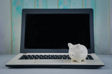 Kumbarası ve dizüstü bilgisayarı masada. Konsept işletme finans teknolojisi, tasarruflar, e-ticaret, e-ticaret, depozito veya çevrimiçi alışveriş, yatırım zenginliği, zengin kar geliri, kazanç, çevrimiçi bankacılık.