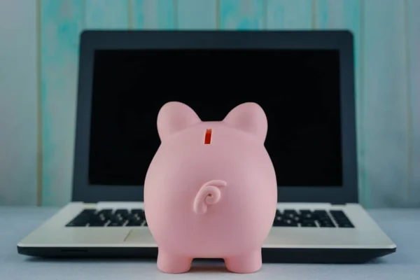 Piggy bank and laptop on table. Concept business finance technology, savings, e-commerce, e-business, deposit or shopping online, wealth from investment, rich profit income, earning, online banking.