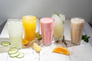 Hafif bir arka planda birçok farklı kokteyl ve milkshake. Uzun bardaklarda renkli alkolsüz kokteyller ve limonatalar.