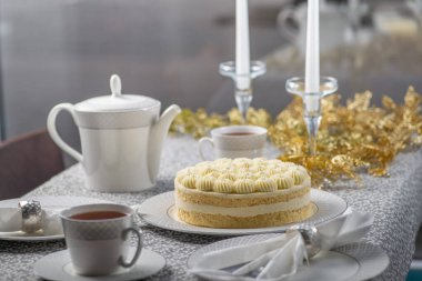 Şenlik, Noel masasına pasta ile servis edildi. Noel ve yeni yıl için aile çay partisi. Altın süslemeler ve mumlarla süslenmiş yemek masası.