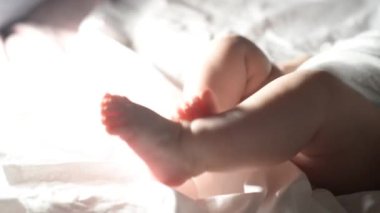 Legs of a newborn baby lie on a white sheet