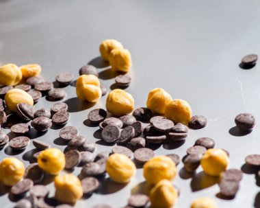 Nuts and chocolate drops on a gray background. Copy space.