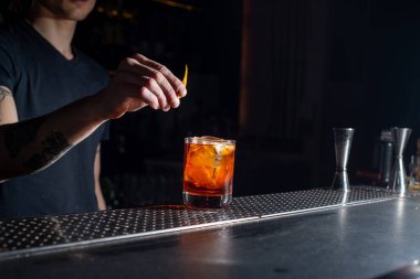 Bartender makes an orange cocktail with citrus fruits. Bar nightlife atmosphere