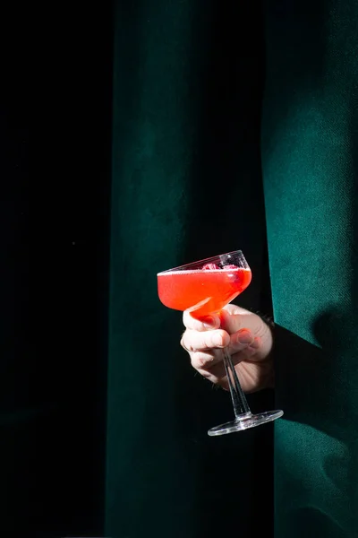 Cocktail red in hand on a velvet background in the bar. Nightlife concept