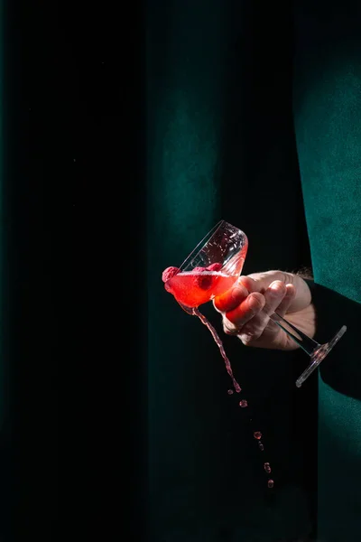 Cocktail red in hand on a velvet background in the bar. Nightlife concept