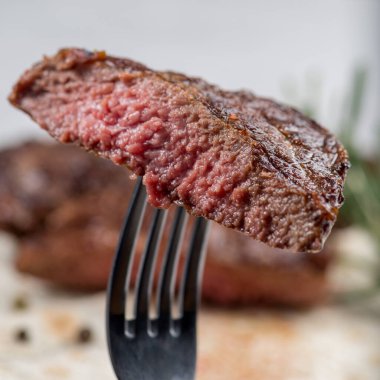 Piece of medium-roasted steak on a fork close-up clipart