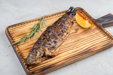 Arka planda kesme tahtasında ızgara uskumru.