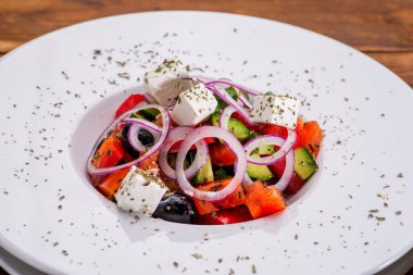 Beyaz kasede peynirli ve taze sebzeli Yunan salatası.