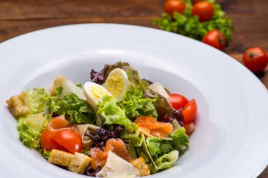 Beyaz tabakta somon ve sebzeli salata. Restoran servisi.