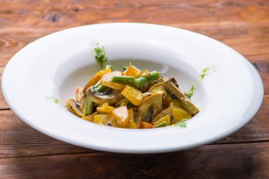 Beyaz bir tabakta sulu sebze ve mantar yahnisi. vejetaryen yemeği