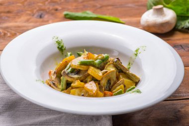 Beyaz bir tabakta sulu sebze ve mantar yahnisi. vejetaryen yemeği