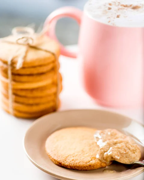 Cookies are smeared with peanut butter. Cup of tea or coffee on background