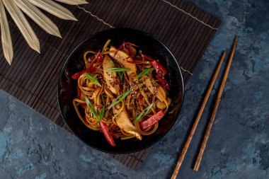 Tavuk ve sebzeli Asya tavuklu erişte ve masada çubuklar. Yukarıdan görüntüle